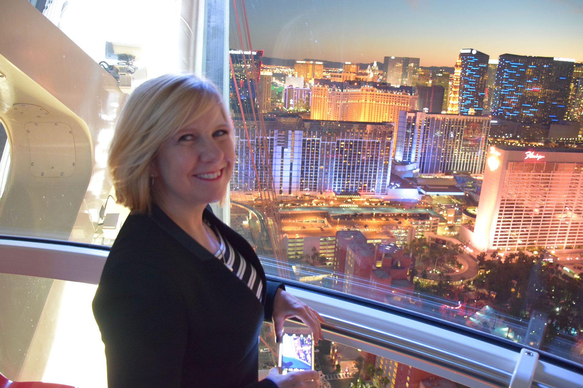 Ronda Tchong smiling on the High Roller observation wheel with the Las Vegas Strip lit up behind her at dusk